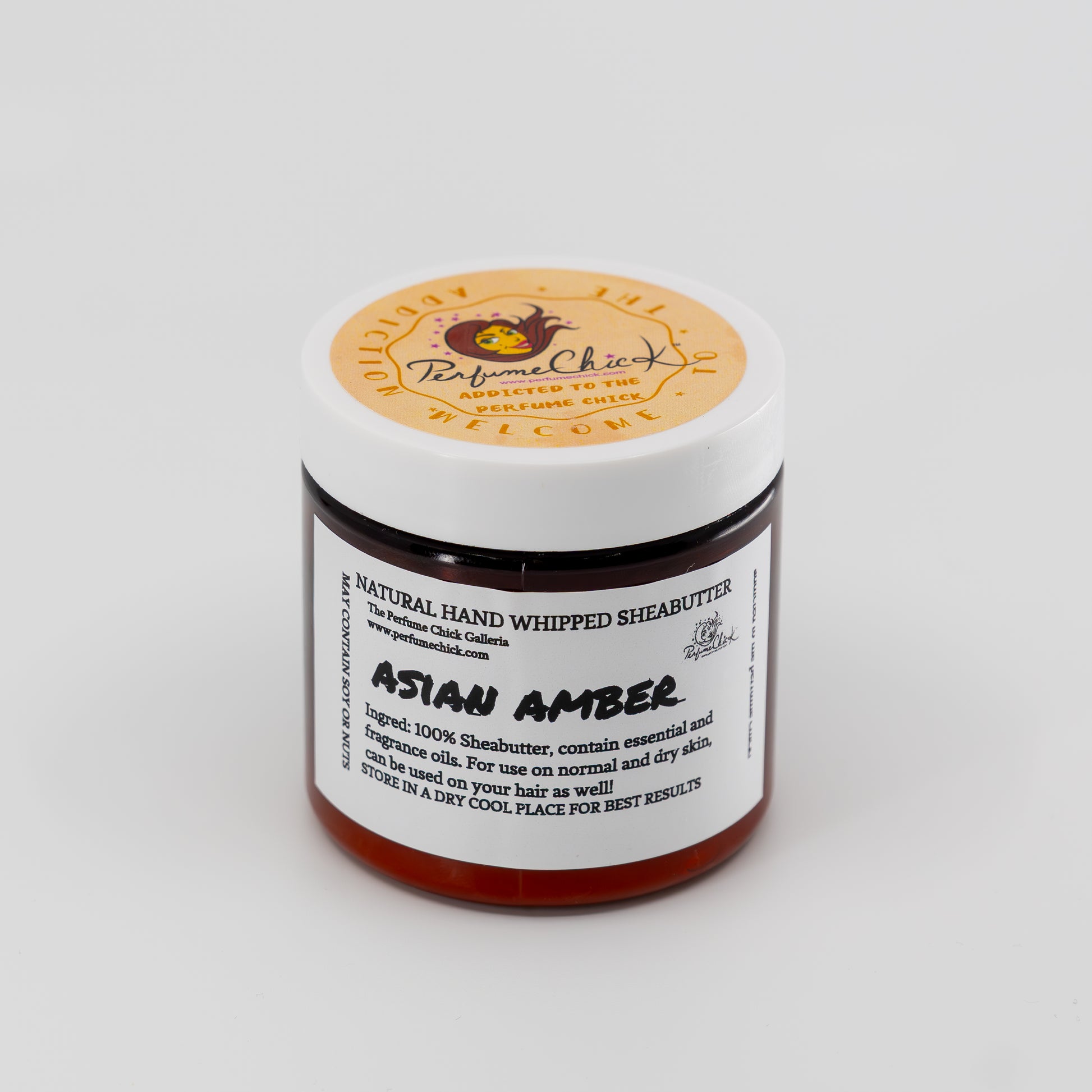 Jar of natural hand whipped shea butter labeled 'Asian Amber' on a white background